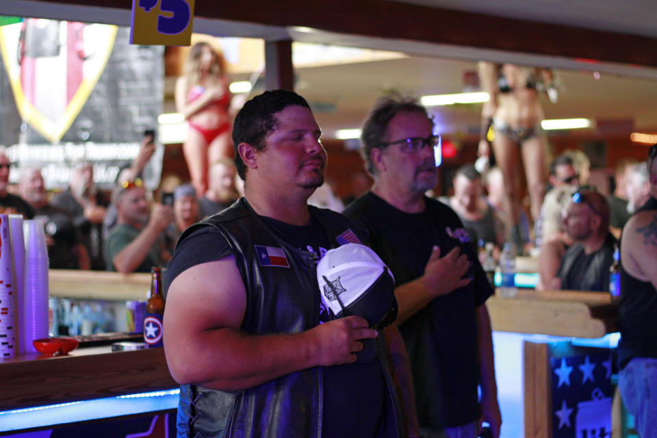 Bikers listen to the national anthem during a Bikers for Trump event at the Sturgis Motorcycle Rally in Sturgis, S.D., on Friday, Aug. 7, 2020. The group has taken advantage of recent motorcycle rallies, which have been some of the largest mass gatherings in the country, to make direct appeals to register to vote. While the group has gained a significant online following for its shows of bravado, it remains to be seen if they can get ballot boxes filled with bikers, many who hail from the suburbs. (AP Photo/Stephen Groves)