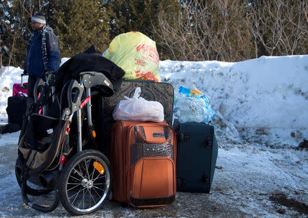 A man claiming to be from Sudan is detained with his family's luggage by a U.S. border patrol officer after his family crossed the U.S.-Canada border into Hemmingford, Canada, from Champlain in New York, U.S., February 17, 2017. REUTERS/Christinne Muschi