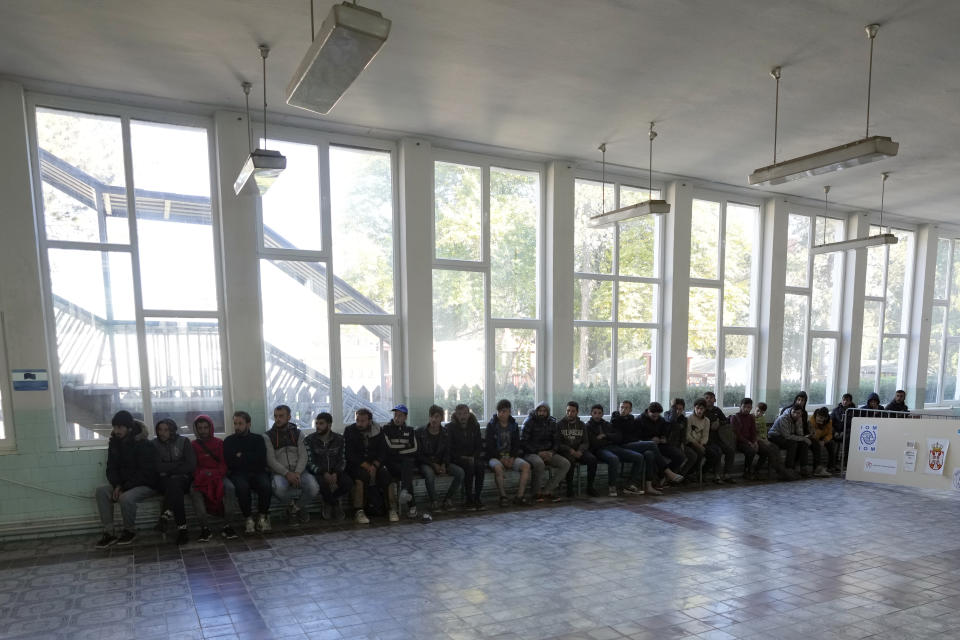 A group of several dozen migrants sat lined up waiting to be registered at reception camp near the southern border with North Macedonia, in Presevo, Serbia, Wednesday, Oct. 19, 2022. Located at the heart of the so-called Balkan route, Serbia recently has seen a sharp rise in arrivals of migrants passing through the country in search of a better future in the West. (AP Photo/Darko Vojinovic)