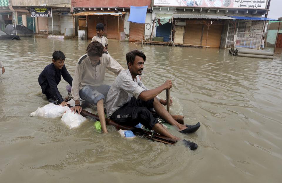 Local residents float through flooded area caused by heavy monsoon rains, in Karachi, Pakistan, Friday, Aug. 28, 2020. Heavy rains hit Pakistan's financial capital Karachi for a fifth straight night, bringing more flooding and killing some more people, officials said, as rescuers evacuated people from flooded neighborhoods. (AP Photo/Fareed Khan)