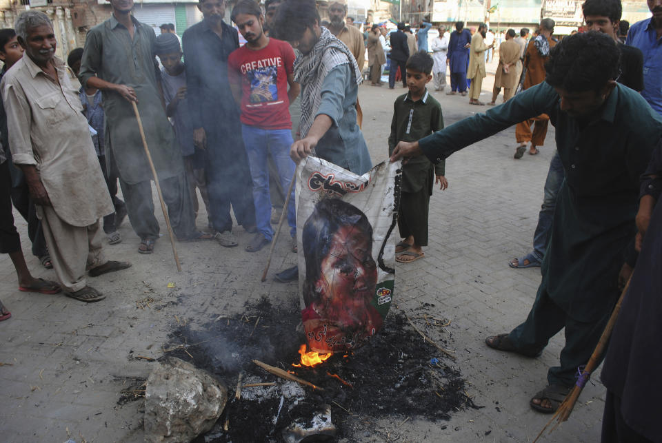 FILE - In this Nov. 1, 2018, file photo, Pakistani protesters burn a poster image of Christian woman Aasia Bibi, in Hyderabad, Pakistan. The Christian woman acquitted after eight years on death row for blasphemy was released but her whereabouts in Islamabad on Thursday, Nov. 8 remained a closely guarded secret in the wake of demands by radical Islamists that she be publicly executed. (AP Photo/Pervez Masih, File)