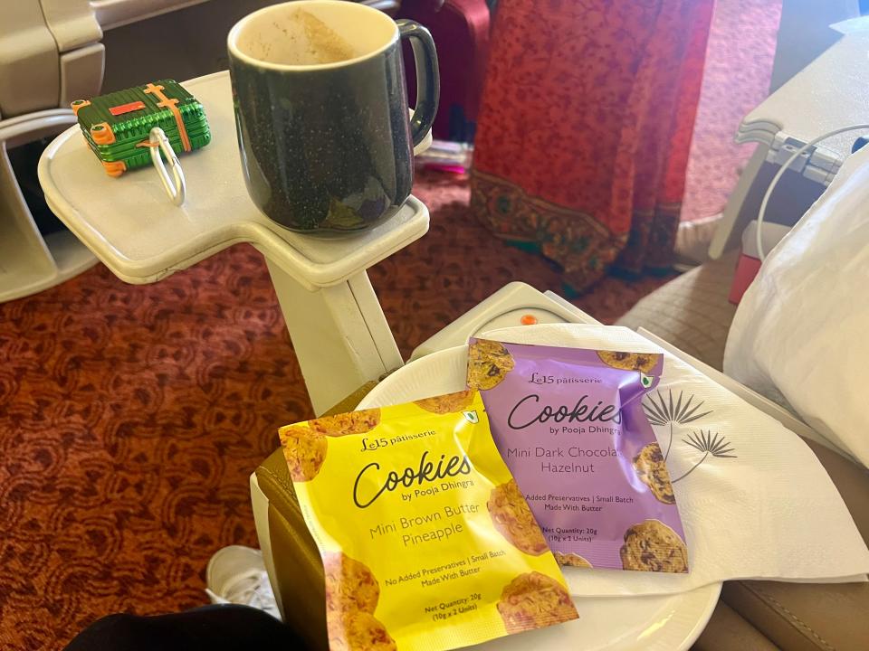 The coffee in a mug on the side table with cookies.