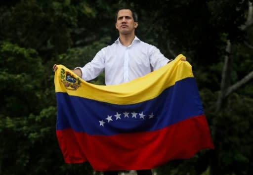 Venezuelan opposition leader Juan Guaido unfurls the country's flag during a rally in Caracas