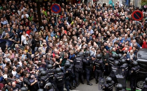 Spanish National riot policemen form a security cordon around the Ramon Llull school  - Credit: EPA/Alberto Estevez