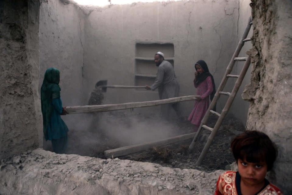 A family clears rubble from their house after it was damaged by an earthquake  in the Behsud district of Nangarhar Province on 28 October 2015 (AFP via Getty Images)