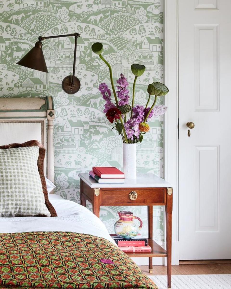 A bedside table decorated with a vase filled with botanicals and a stack of books