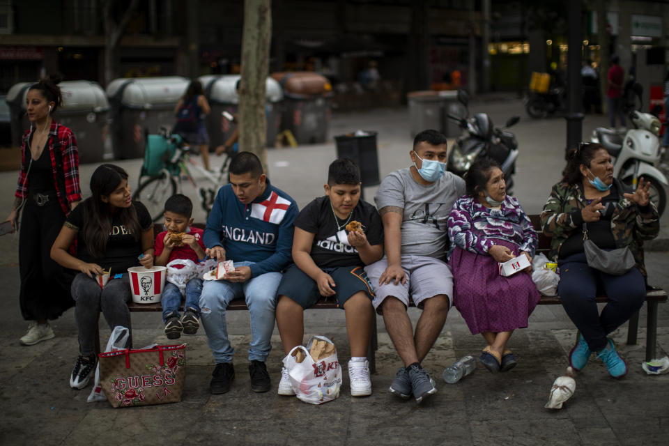 Family members eat as they sit on a bench in Barcelona, Spain, Sunday, May 31, 2020. Spanish Prime Minister Pedro Sánchez says he will ask Spain's Parliament for a final two-week extension of the nation's state of emergency that has allowed the government to take lockdown measures to control its coronavirus outbreak. (AP Photo/Emilio Morenatti)