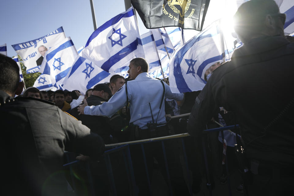 An Israeli police officer blocks right wing activists from marching towards Jerusalem's Old City, in Jerusalem, Wednesday, April 20, 2022. Police prevented hundreds of ultra-nationalist Israelis from marching around predominantly Palestinian areas of Jerusalem's Old City. The event planned for Wednesday was similar to one that served as one of the triggers of last year's Israel-Gaza war. (AP Photo/Ariel Schalit)