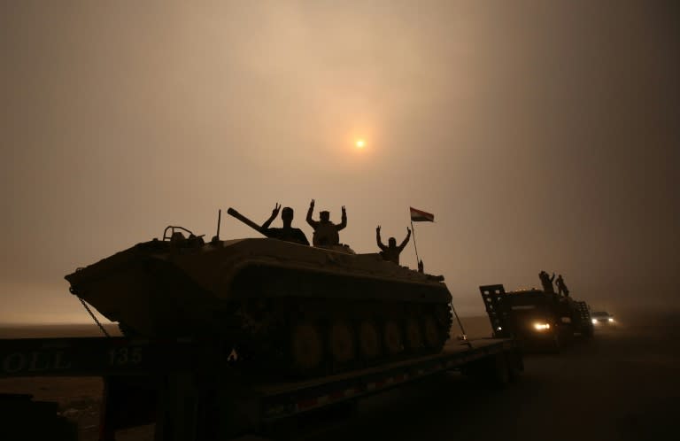 Iraqi forces flash the V-sign from an infantry fighting vehicle loaded on a truck driving through the Al-Shura area, south of Mosul, on October 24, 2016, during an operation to retake the main hub city from IS group