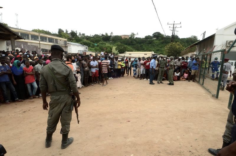 Security officials stand guard as people wait for friends and relatives as a ship carrying more than 1,000 people fleeing an attack claimed by Islamic State-linked insurgents on the town of Palma, docks in Pemba