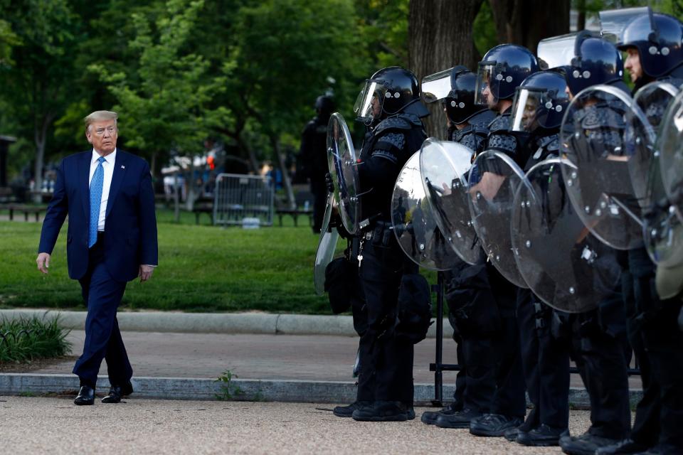 President Donald Trump walks past police in Lafayette Park after he visited St. John's Church across from the White House on June 1. Part of the church was set on fire during protests the night before.