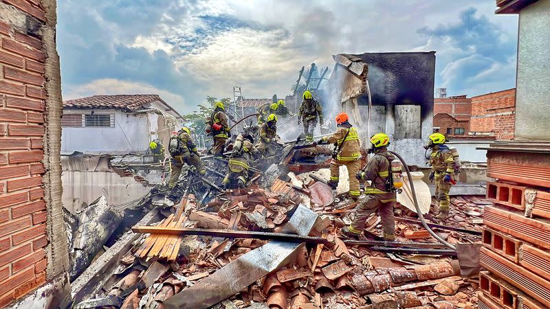 Bomberos remueven escombros en la zona en donde un pequeño avión cayó a tierra y provocó la muerte de sus ocho ocupantes en Medellín