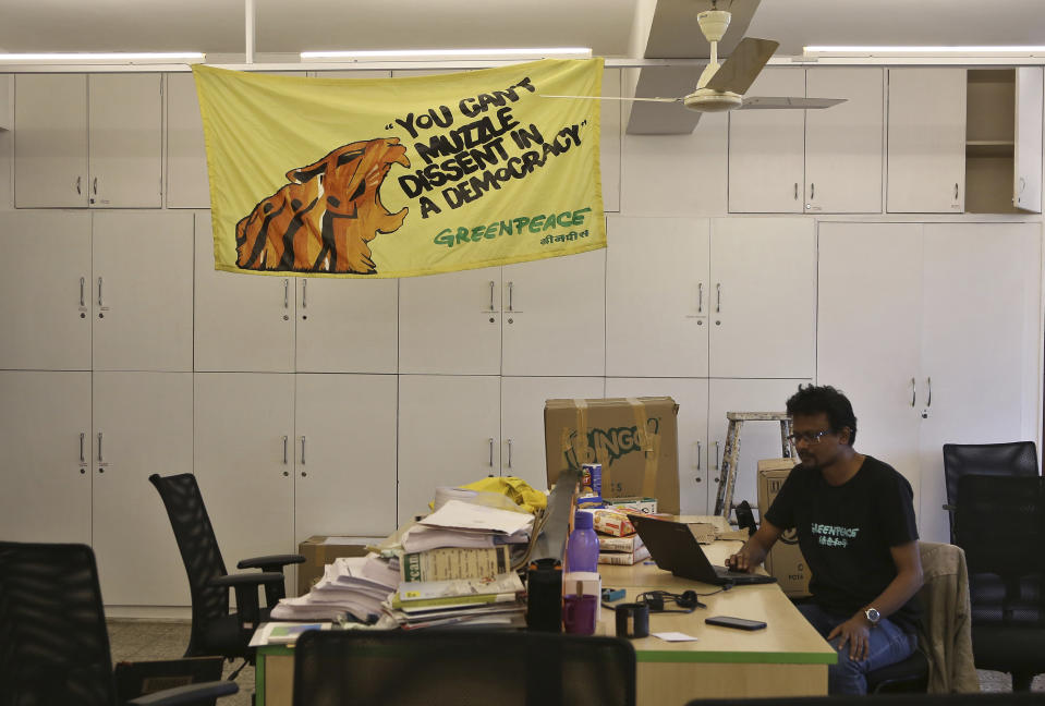 A Greenpeace India employee works under a banner displayed at their only operational office in Bangalore, India, Tuesday, Feb. 5, 2019. International rights groups and foreign aid organizations with deep roots in India say they are struggling to operate under the administration of Prime Minister Narendra Modi, whose Hindu nationalist Bharatiya Janata Party has elevated the role of homegrown social groups while cracking down on foreign charities. (AP Photo/Aijaz Rahi)