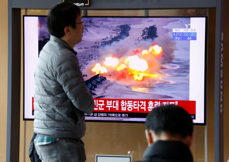 A man walks past a TV showing a file picture for a news report on North Korea firing two unidentified projectiles, in Seoul