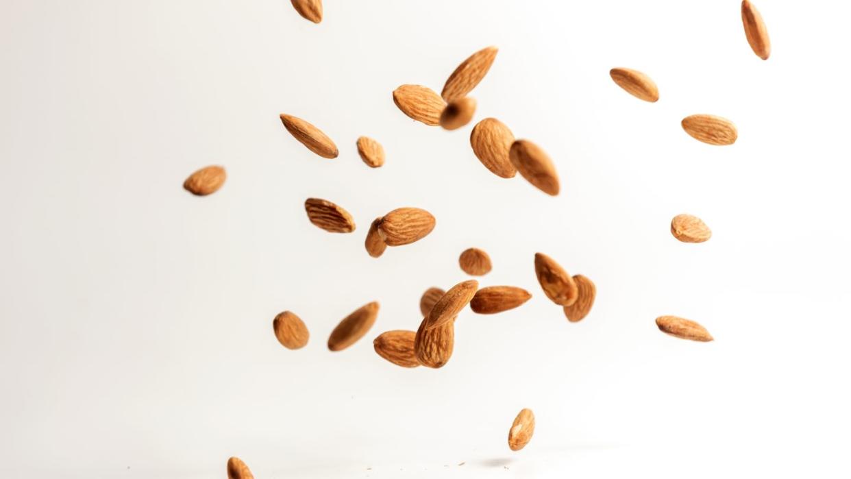 flying almond nuts on white background