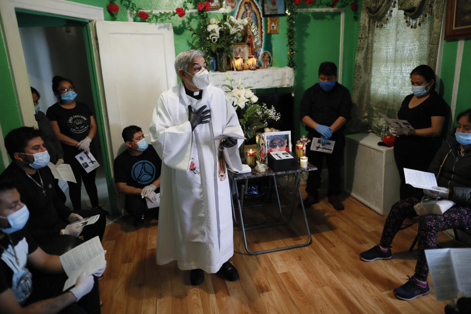 The Rev. Fabian Arias offers a homily as he performs an in-home service beside the remains of Raul Luis Lopez who died from COVID-19 the previous month, Saturday, May 9, 2020, in the Corona neighborhood of the Queens borough of New York. (AP Photo/John Minchillo)