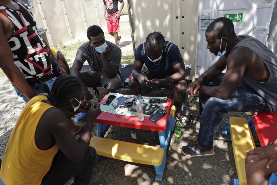 Haitian migrants gather to repair their mobile phones at a migrant camp amid the new coronavirus pandemic in San Vicente, Darien province, Panama, Tuesday, Feb. 9, 2021. Panama is allowing hundreds of migrants stranded because of the pandemic, to move to the border with Costa Rica, after just reopening its land borders. (AP Photo/Arnulfo Franco)