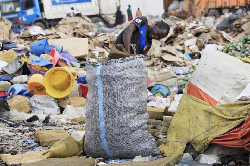 In this photo taken Friday, Jan, 24. 2014, a scavenger in Lagos, Nigeria sorts out iron and plastic to sell at the Olusosun dump site the city's largest dump. With a population of more than 20 million, garbage piles up on streets, outside homes and along the waterways and lagoons, creating eyesores and putrid smells. The booming city also has major electricity shortages and many residents rely on diesel generators that cloud the air with black exhaust. Nigeria's most populous city is turning these problems into an advantage by starting a program to convert waste into methane gas to generate electricity. A pilot program at a local market has already shown success on a smaller scale. Lagos’ waste management program is also organizing recycling to clean up the country's biggest city. (AP Photo/ Sunday Alamba)