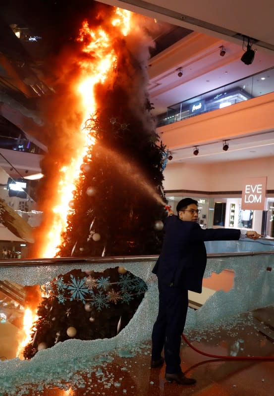 A man tries to extinguish a burning Christmas tree at Festival Walk mall in Kowloon Tong, Hong Kong