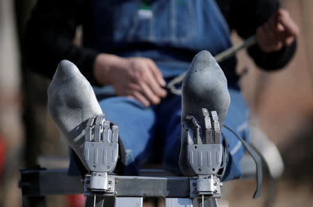 Geng Shuai, dubbed "Useless Edison" by his fans, fastens the belts as he poses on his invention "happy chair", a workout bench with robotic arms to tickle the underarms and the feet, outside his workshop in Yangcun village of Baoding, Hebei province, China January 22, 2019. REUTERS/Jason Lee