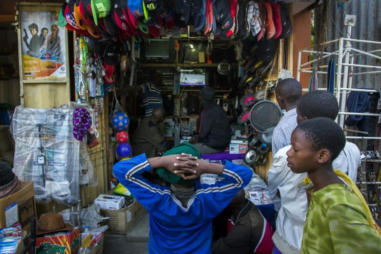 People gather at a store to watch the news as Pope Francis arrives at Jomo Kenyatta International Airport in Nairobi on November 25, 2015