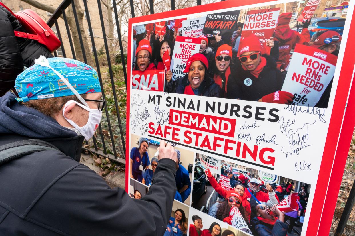 Zach Clapp, a nurse in the Pediatric Cardiac ICU at Mount Sinai Hospital, signs a board demanding safe staffing during a rally by NYSNA nurses from NY Presbyterian and Mount Sinai, March 16, 2021, in New York.