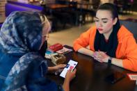 Iranian woman Atefeh Khani and her friend checks the "Hamdam" dating app on her phone in a cafe in Tehran