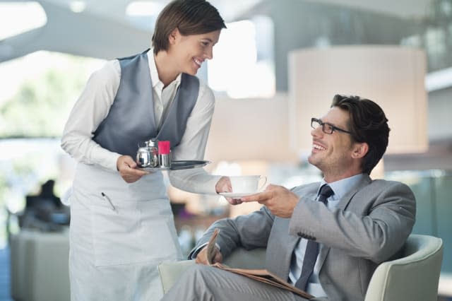 Waitress serving businessman cup of coffee in hotel lounge