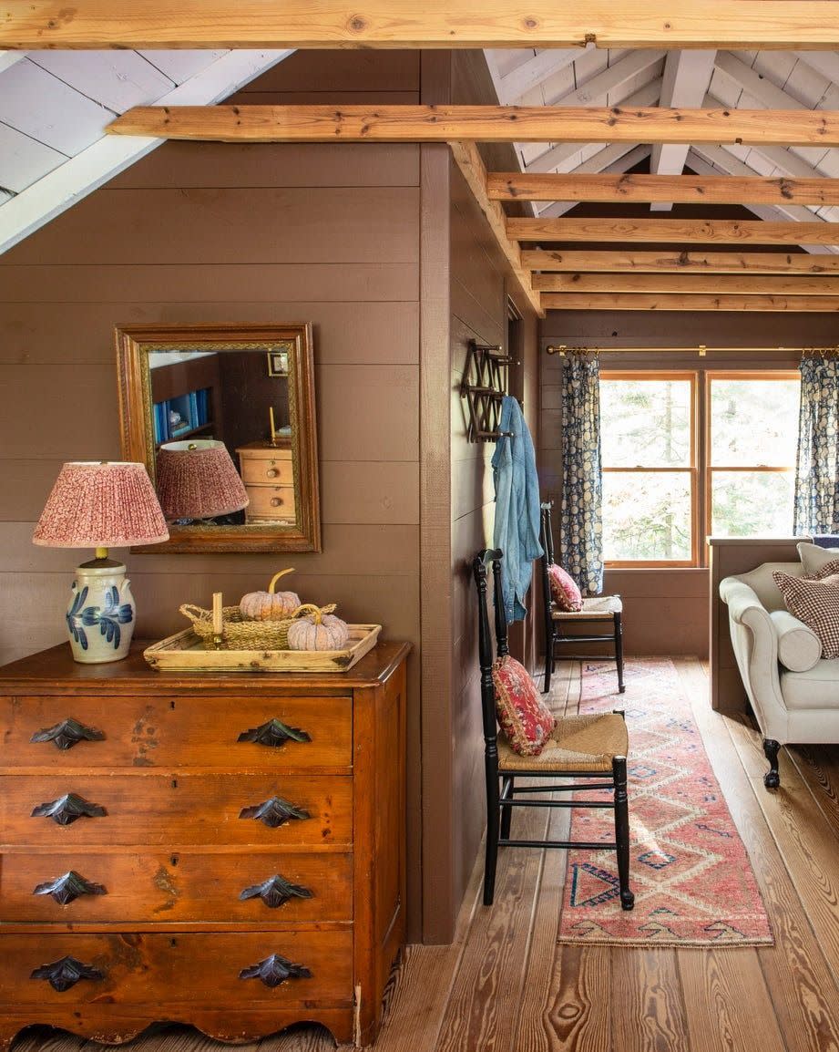 upper loft area with brown wood walls and exposed ceiling rafters