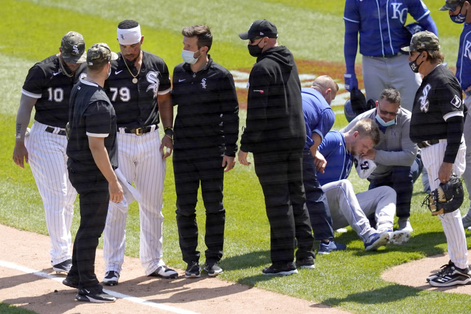 Chicago White Sox's Jose Abreu, left, heads to the dugout as Kansas City Royals' Hunter Dozier tries to get up after they collided along the first base line in the second inning of the first game of a baseball doubleheader Friday, May 14, 2021, in Chicago. (AP Photo/Charles Rex Arbogast)