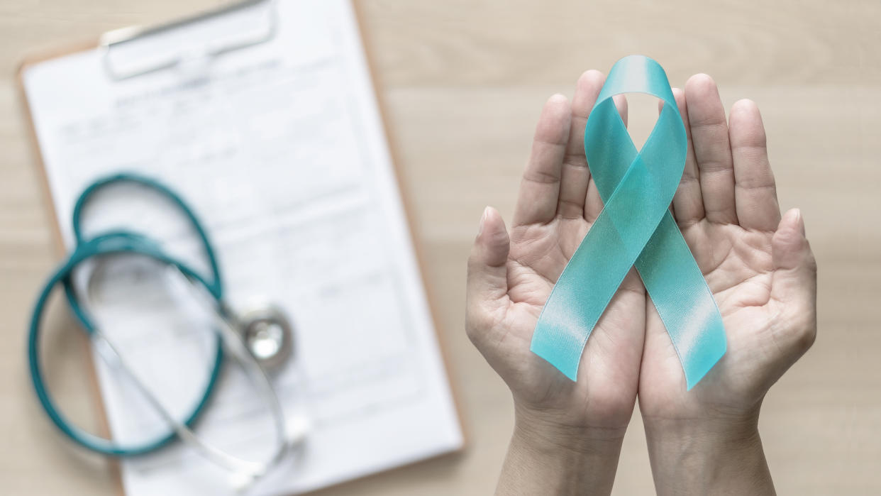 Teal ribbon awareness on woman's hand for Ovarian Cancer, Polycystic Ovary Syndrome (PCOS) disease, Post Traumatic Stress Disorder (PTSD), Tourette's Syndrome, Obsessive Compulsive Disorder (OCD)