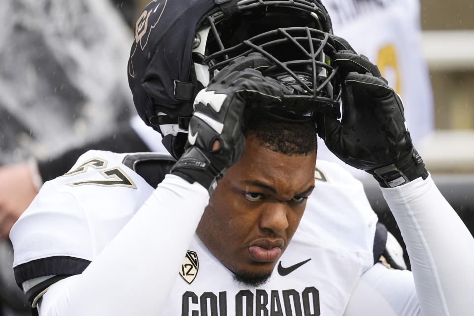Colorado offensive tackle Khalil Benson pulls on his helmet as he warms up before the team's spring NCAA college football game, Saturday, April 27, 2024, in Boulder, Colo. (AP Photo/David Zalubowski)