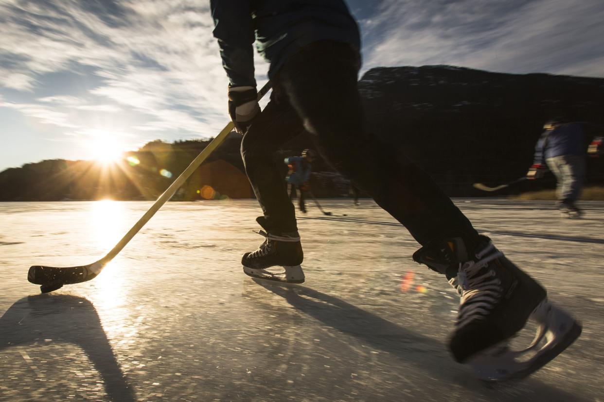 people playing ice hockey on frozen lake in sunset