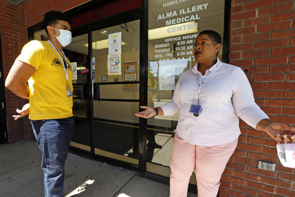 In this photo made on Monday, July 20, 2020, Kiva A. Fisher-Green, right, talks with fellow social worker Tyree R. Ford outside the Alma Illery Medical Center in Pittsburgh. In March and April when Philadelphia and its surroundings became one of the nation's hot-spots for COVID-19 cases, Pittsburgh seemed at the time, to be under more control: the city racked up a fraction of the coronavirus cases as the other side of Pennsylvania. But by the beginning of July, officials in Pittsburgh's Allegheny County, began a cascading shutdown of bars, restaurants and gatherings due to an alarming spike in COVID-19 cases. (AP Photo/Gene J. Puskar)