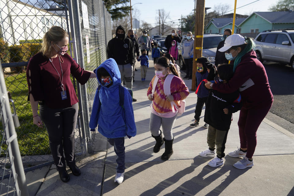 FILE - In this Feb. 25, 2021, file photo, Assistant Principal Janette Van Gelderen, left, welcomes students at Newhall Elementary in Santa Clarita, Calif. Gov. Gavin Newsom signed a new law Friday, March 5, with $6.6 billion in incentives to try to get more California schools to reopen. The response has been lukewarm support, as teachers resist and parents complain that it doesn't do enough to get kids in the classroom. (AP Photo/Marcio Jose Sanchez, File)