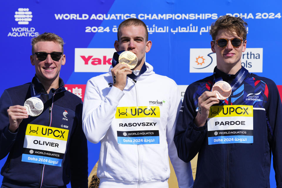 Silver medalist Marc-Antonie Oliver of France, gold medalist Kristof Rasovszky of Hungary and bronze medalist Hector Pardoe of Great Britain, from left, pose on the podium of the men's 10 km open water final at the World Aquatics Championships in Doha, Qatar, Sunday, Feb. 4, 2024. (AP Photo/Hassan Ammar)