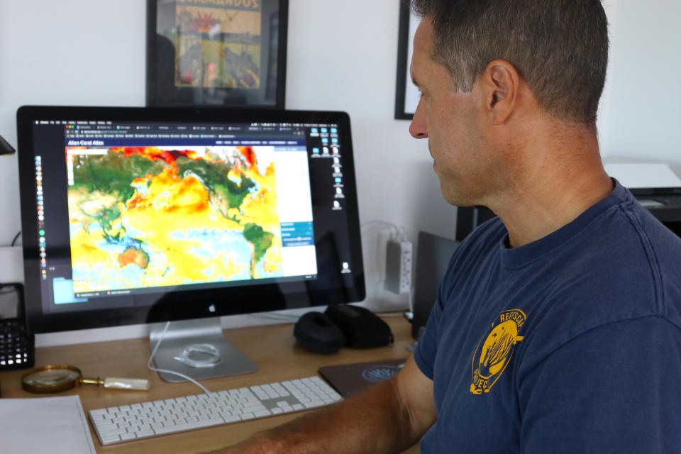 In this Sept. 13, 2019 photo, ecologist Greg Asner, the director of Arizona State University's Center for Global Discovery and Conservation Science, reviews ocean temperature data at his lab on the west coast of the Big Island near Captain Cook, Hawaii. "Nearly every species that we monitor has at least some bleaching," said Asner after a dive in Papa Bay. (AP Photo/Caleb Jones)