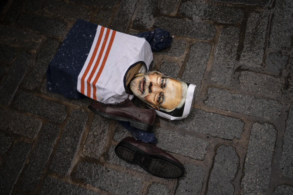 An effigy of Narendra Modi, prime minister of India, lies on the ground as protesters gather outside the Consulate General of India, Tuesday, Jan. 26, 2021, in the Manhattan borough of New York. Tens of thousands of protesting farmers have marched, rode horses and drove long lines of tractors into India's capital, breaking through police barricades to storm the historic Red Fort. The farmers have been demanding the withdrawal of new laws that they say will favor large corporate farms and devastate the earnings of smaller scale farmers. Republic Day marks the anniversary of the adoption of India’s constitution on Jan. 26, 1950. (AP Photo/John Minchillo)