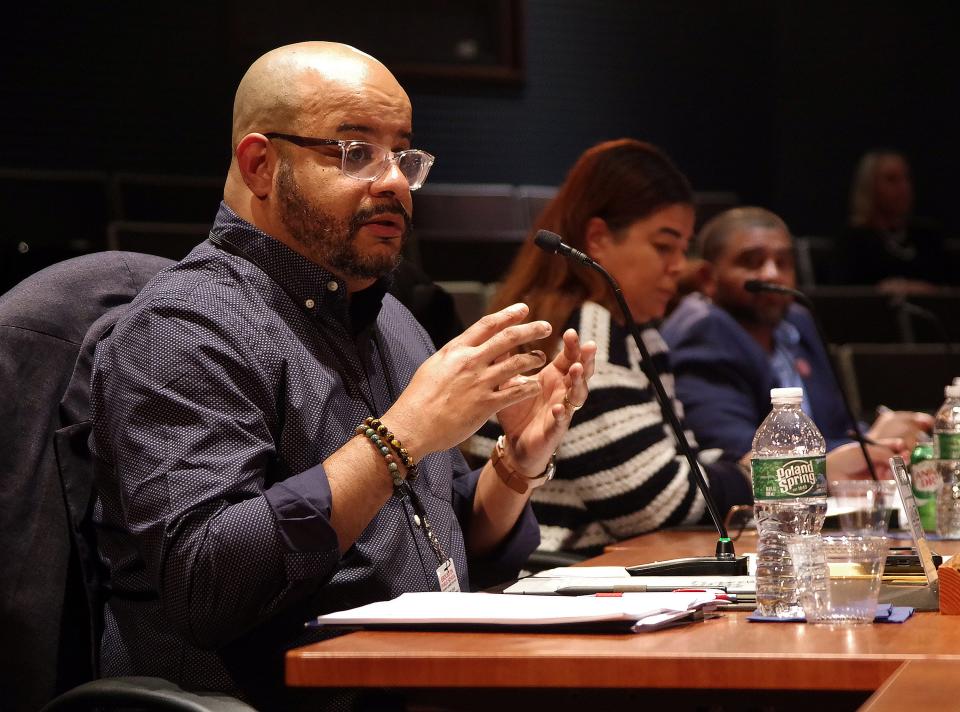 Jorge Vega, one of the newest members of the Brockton School Committee, speaks to Patricia Boyer of the school business office during the School Committee meeting on May 15, 2024. Next to Vega are fellow committee members Ana C. Oliver and Tony A. Rodrigues.