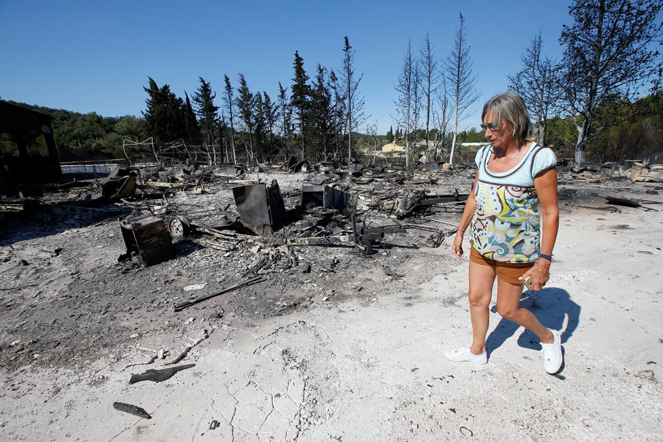 <p>A woman walks past charred debris of vehicles that were destroyed by fire in a parking lot for camping cars in Bormes-les-Mimosas, in the Var department, France, July 26, 2017, after firefighters evacuated thousands of campers and local residents when a wildfire broke out on France’s tourist-thronged Riviera coast overnight. (Jean-Paul Pelissier/Reuters) </p>