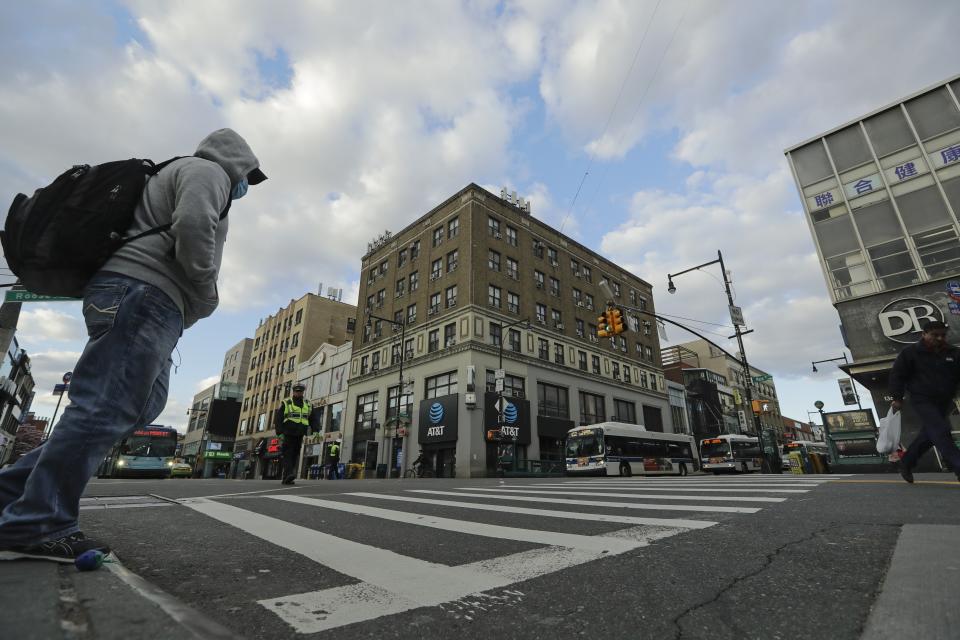 Pedestrians wear personal protective equipment as they cross Main Street Wednesday, April 1, 2020, in the Flushing section of the Queens borough of New York. The new coronavirus causes mild or moderate symptoms for most people, but for some, especially older adults and people with existing health problems, it can cause more severe illness or death. (AP Photo/Frank Franklin II)