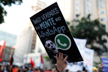 A woman holds a sign with an image of presidential candidate Jair Bolsonaro that reads "He lies in WhatsApp," during a protest against Bolsonaro in Sao Paulo, Brazil, October 20, 2018. REUTERS/Nacho Doce