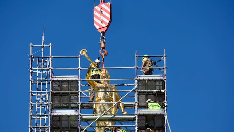 The Angel Moroni statue is lifted into place on the Salt Lake Temple, Tuesday, April 2, 2024.