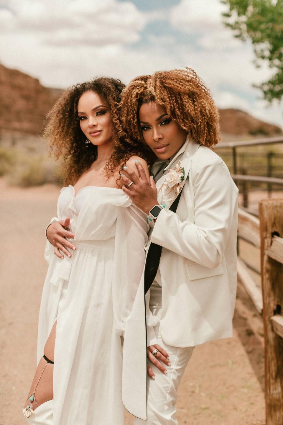 Two brides embrace in a desert.