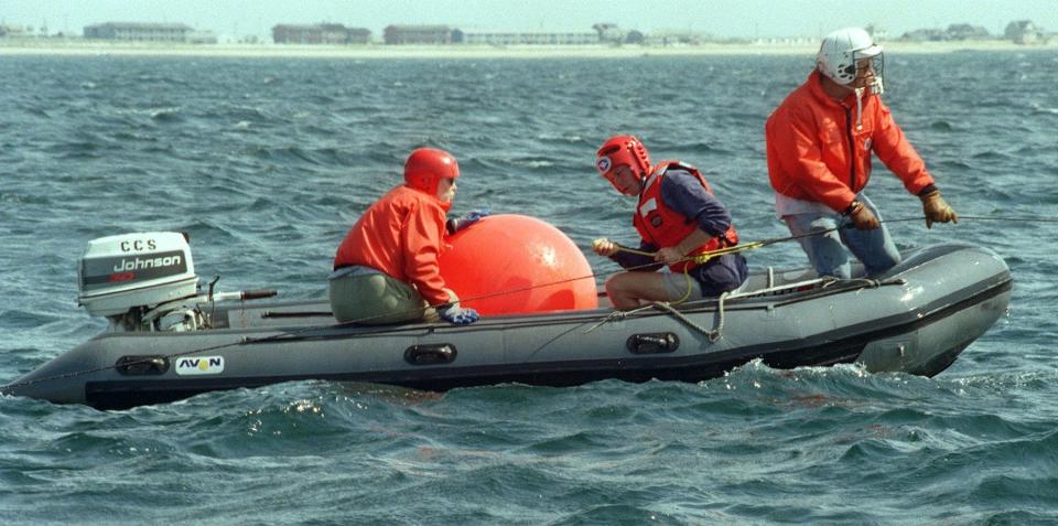 In a 1998 photo, Charles "Stormy" Mayo, right, director of the Center for Coastal Studies right whale ecology program, pulls on lobster gear attached to a North Atlantic right whale swimming off Provincetown Harbor.