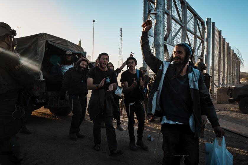 EREZ CROSSING, ISRAEL -- FEBRUARY 29, 2024: Several Right wing activists and Jewish settlers celebrate and clutch strawberries after breaching into Gaza and got apprehended by Israeli forces as many more arrive to demonstrate at the Gaza border at Erez Crossing, Israel, Thursday, Feb. 29, 2024. About a hundred Israelis stormed Erez Crossing at the northern tip of Gaza an attempt to re-establish Jewish settlements in the Strip since the war began. A few demonstrators managed to breach into Gaza on foot by several hundred meters getting apprehended by Israeli soldiers. They returned to the border clutching strawberries and were celebrated. At least 2 dozen more entered the military buffer zone between Israel and Gaza carrying construction material and building. They built two symbolic OoutpostO and demonstrated next to it for several hours without any interference from Israeli forces.(MARCUS YAM / LOS ANGELES TIMES)