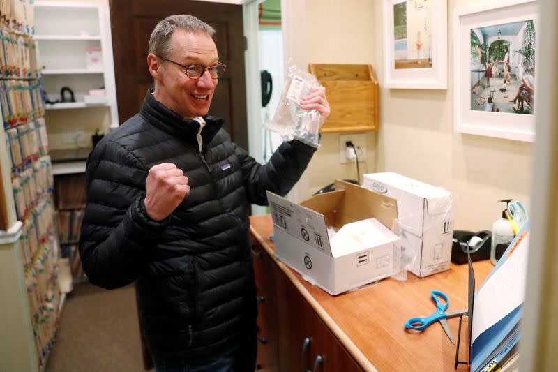 Dr Greg Gulbransen reacts after opening a package of hand sanitizer as he maintains visits with both his regular patients and those confirmed to have the coronavirus disease (COVID-19) at his pediatric practice in Oyster Bay, New York