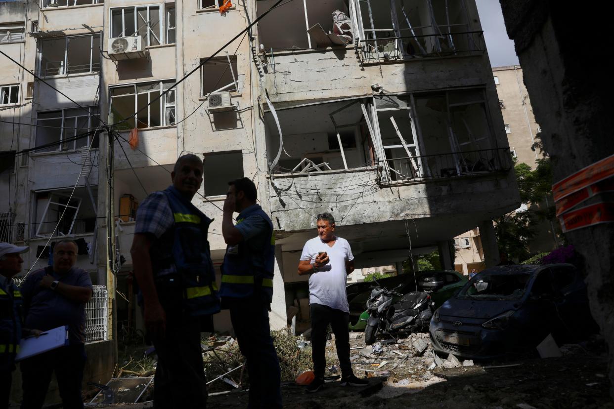 People inspect the damage of their apartment building after it was hit by a rocket fired from the Gaza Strip overnight in Petah Tikva, central Israel, Thursday, May 13, 2021.