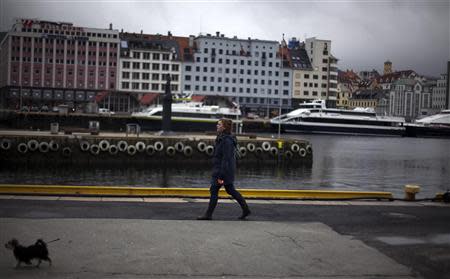 A woman walks her dog near the marina in downtown Bergen, southwestern Norway, in this March 20, 2012 file photo. REUTERS/Stoyan Nenov/Files