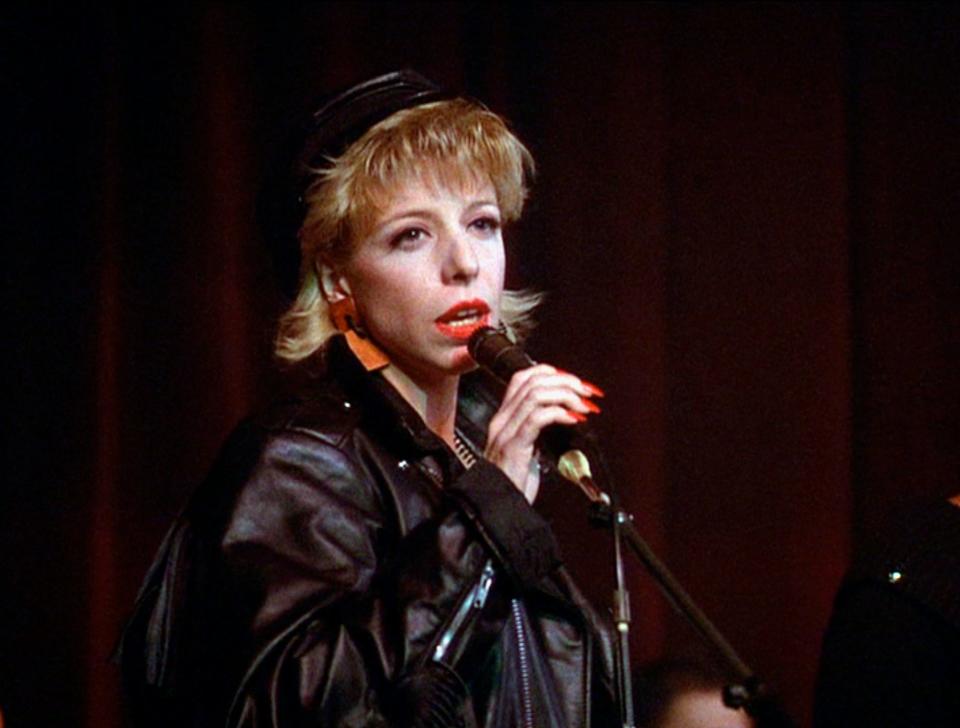 Julee Cruise in a leather jacket holding a microphone